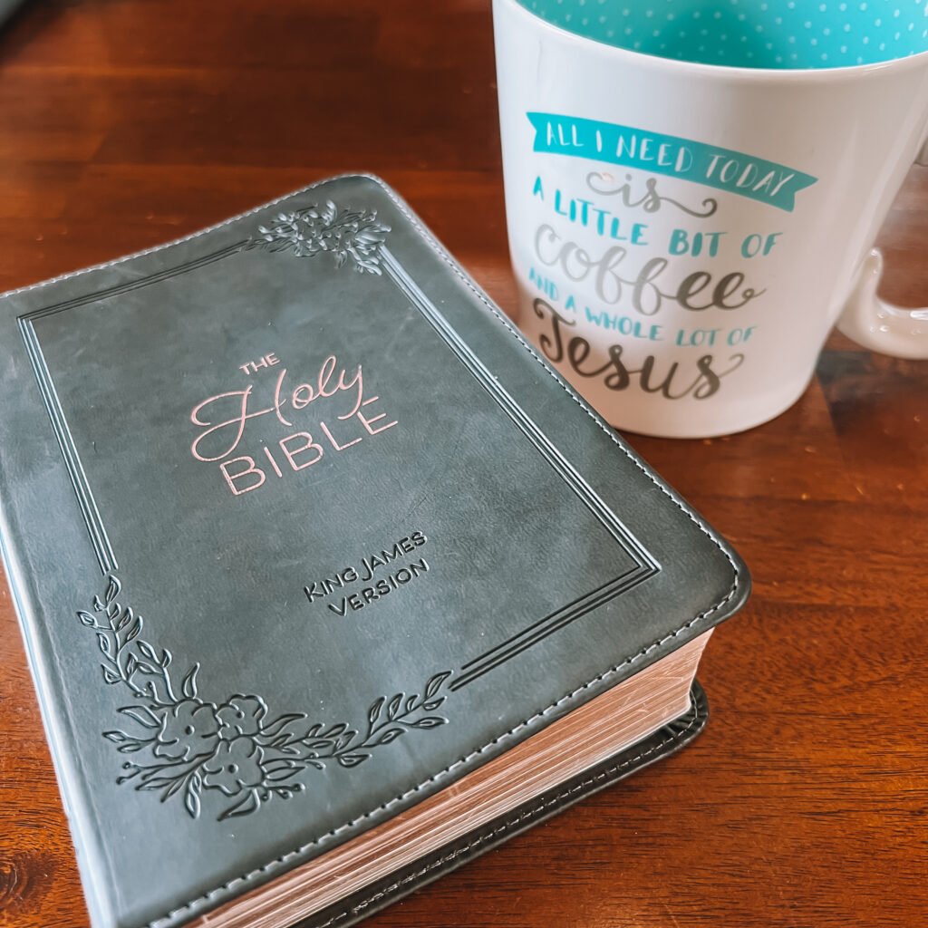 The Holy Bible and a coffee cup on a table.
