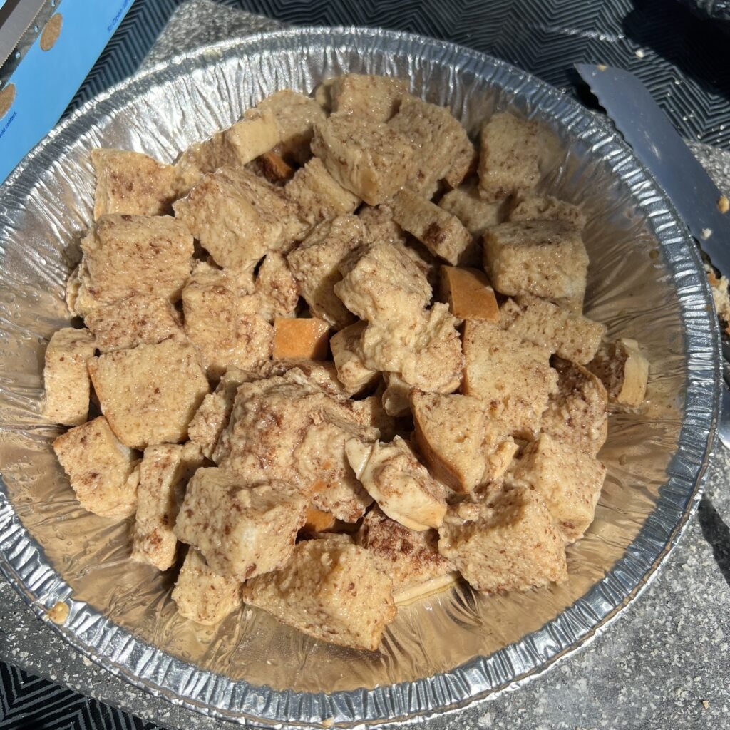 Putting the soaked sourdough pieces in the pie tin to cook the french toast bake.