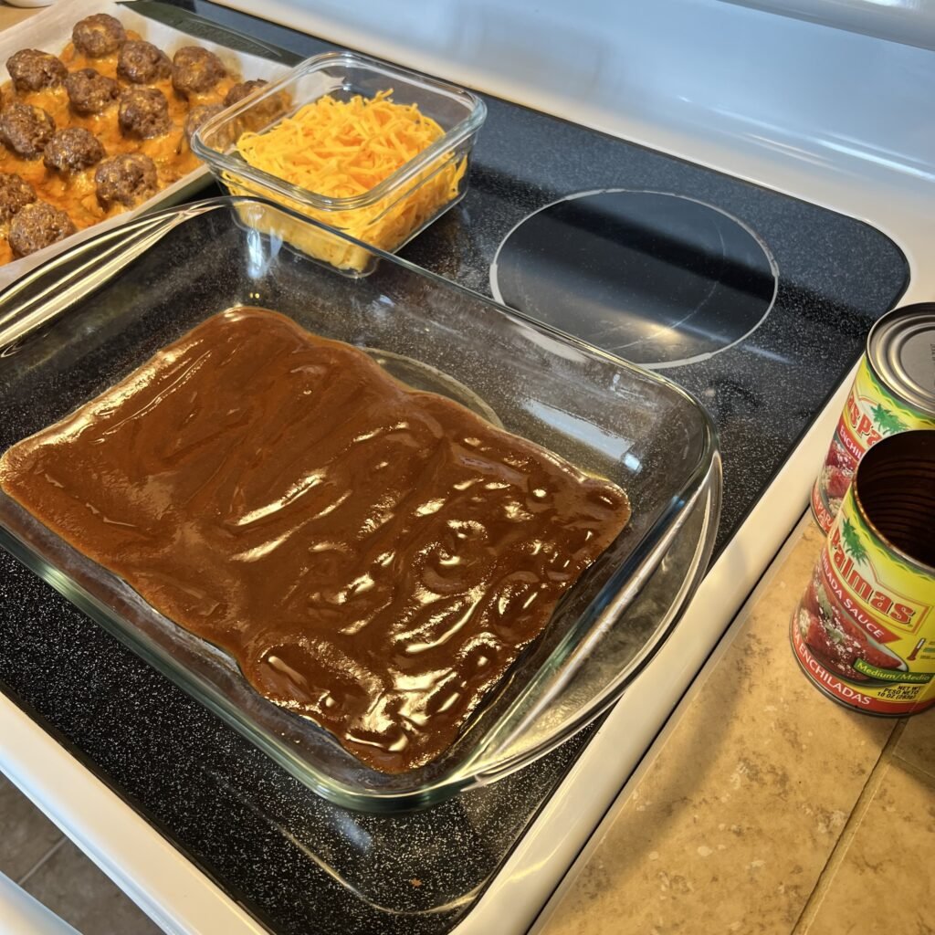 Preparing a cheesy keto enchilada meatball bake.