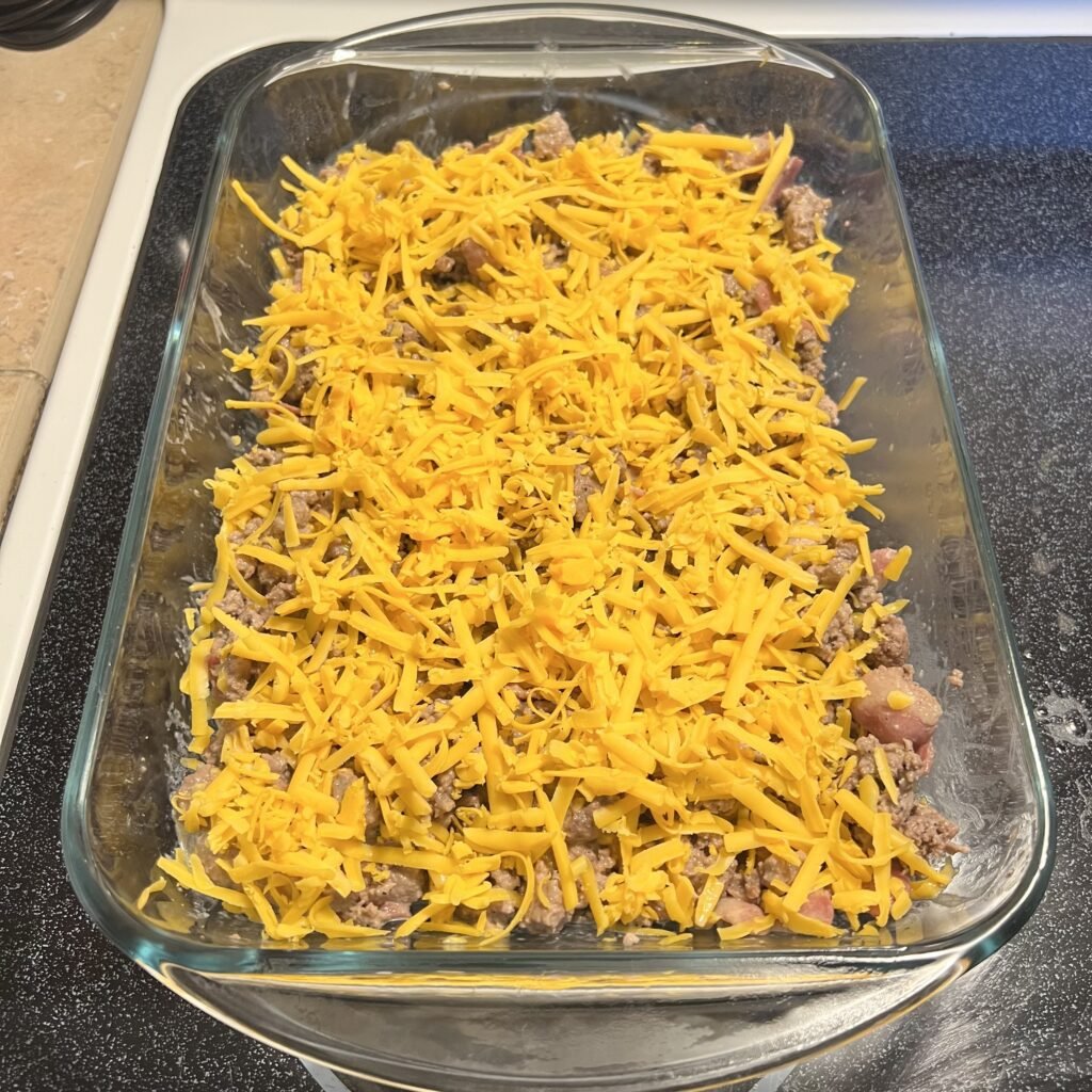 A prepared cheesy bacon and beef carnivore casserole ready to go into the oven for baking.