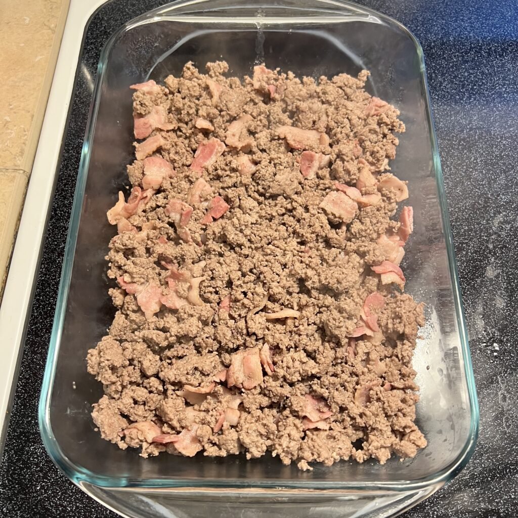 Ground beef and bacon mixture is the base layer of this delicious carnivore casserole. Here you can see it in the prepared 9x13 baking dish.