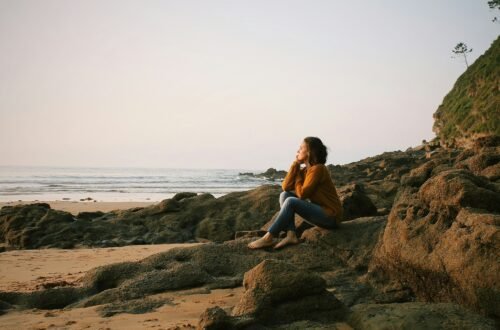A woman peacefully sitting on the beach.