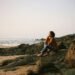 A woman peacefully sitting on the beach.