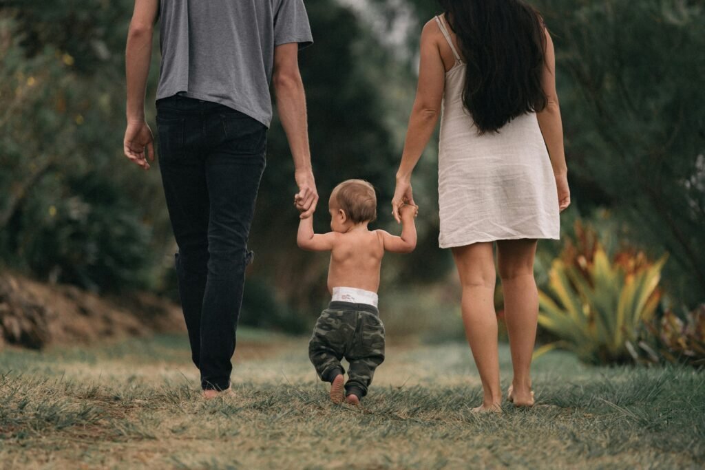 Parents walking with their toddler through a beautiful outdoor landscape.