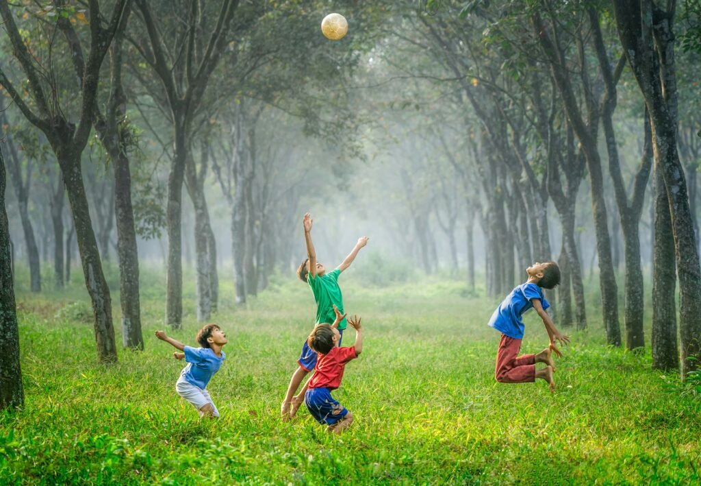 A group of energetic and joyful kids playing soccer in a forest.