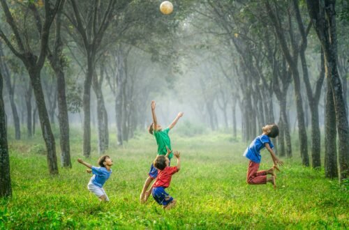 A group of energetic and joyful kids playing soccer in a forest.
