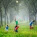 A group of energetic and joyful kids playing soccer in a forest.