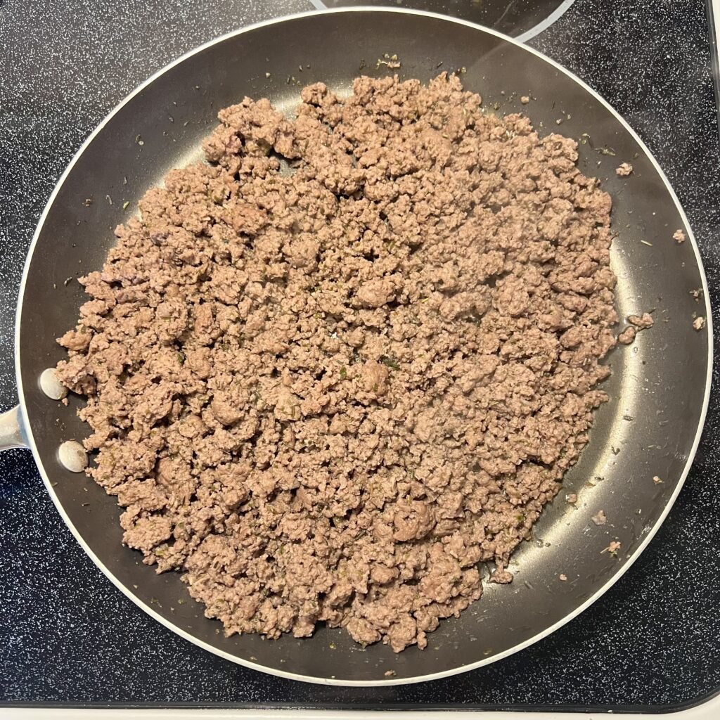 Overhead shot of browned and seasoned ground beef in a frying pan.