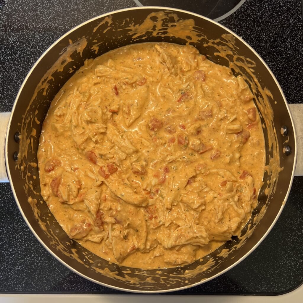 An overhead shot of a pot of creamy shredded chicken with Rotel and marinara.