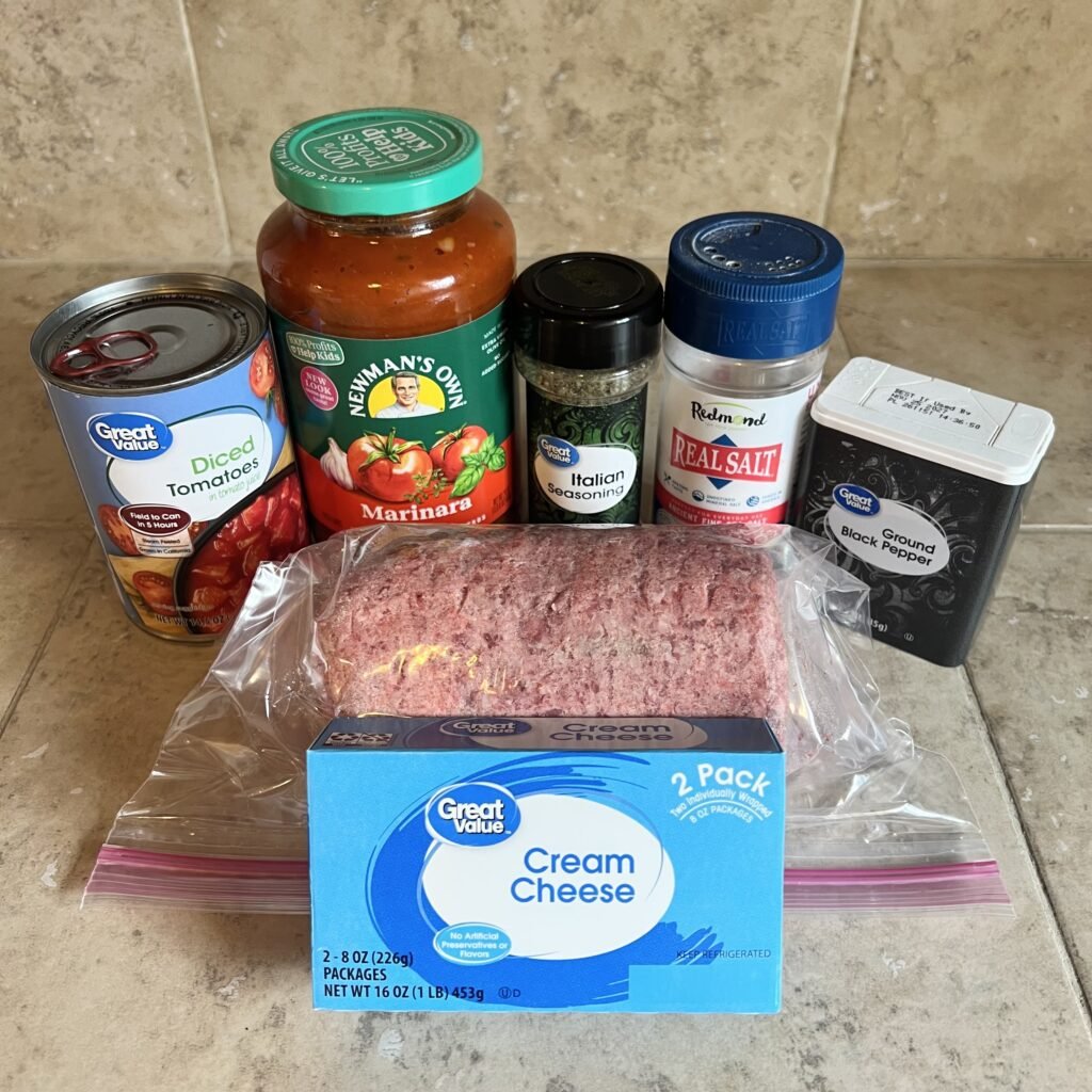 Kitchen countertop with all the ingredients needed to make a creamy ground beef skillet with tomatoes and marinara.