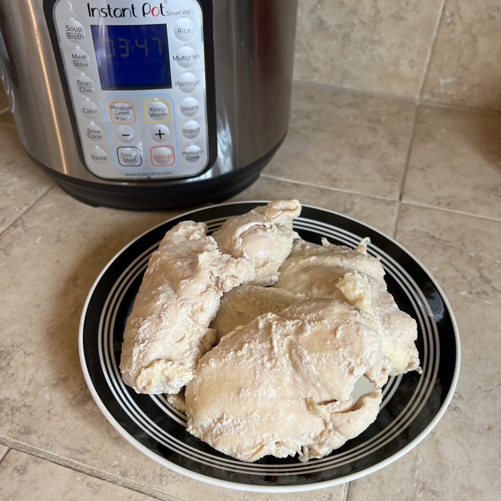 Fresh cooked and juicy chicken breasts sitting on a plate next to the instant pot. Ready to be served or added to your favorite chicken dishes.