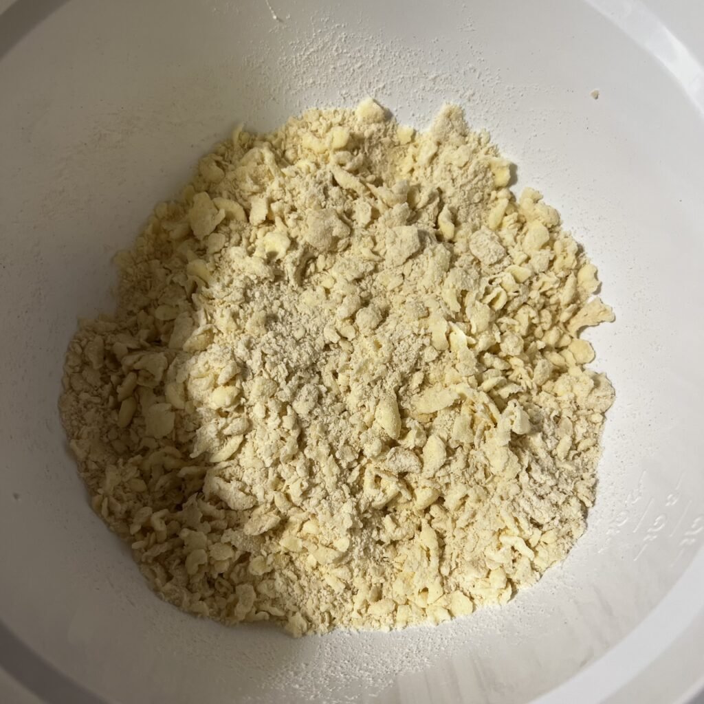The sourdough pie crust dough mixture mixed in a large white mixing bowl.