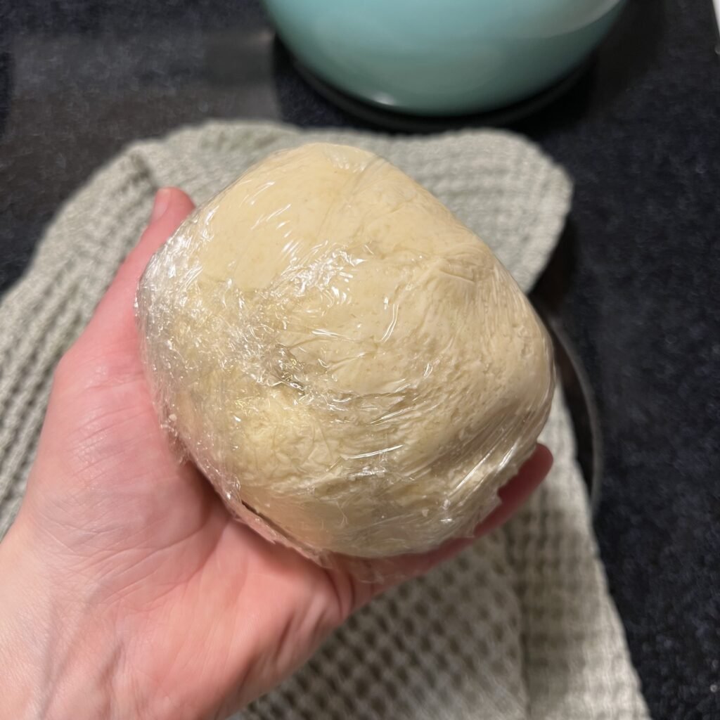 A freshly made and wrapped sourdough pie crust dough ball ready to be stored in the fridge or freezer.