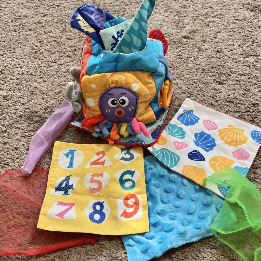 The various colors, textures, and picture on the Baby Tissue Box learning toy.