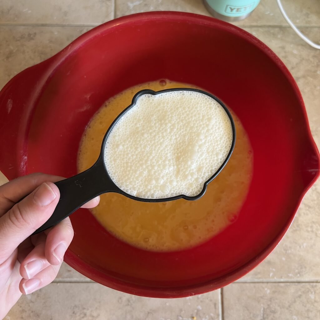 An overhead shot of one cup of cream above a bowl of scrambled eggs.