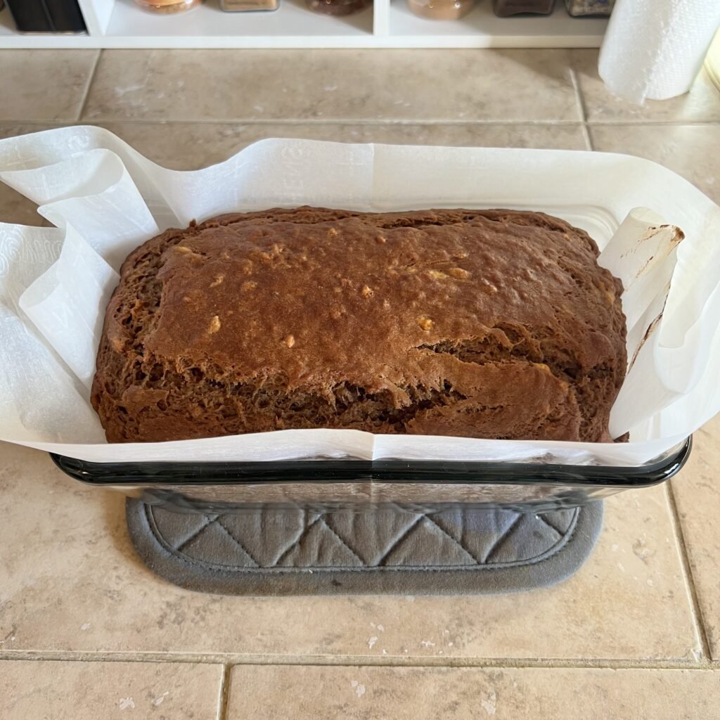 Freshly baked sourdough banana bread in a parchment-lined glass bread baking pan.