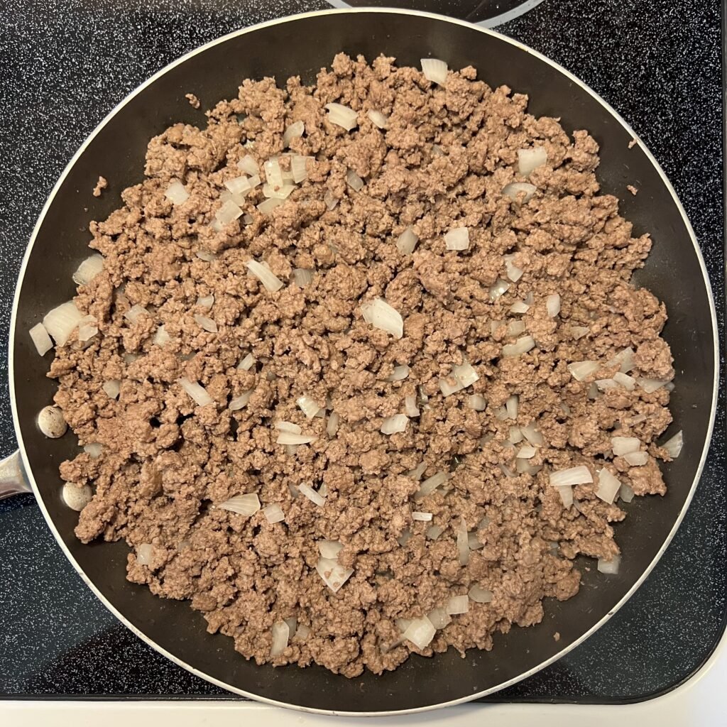 A frying pan full of browned ground beef and onions.
