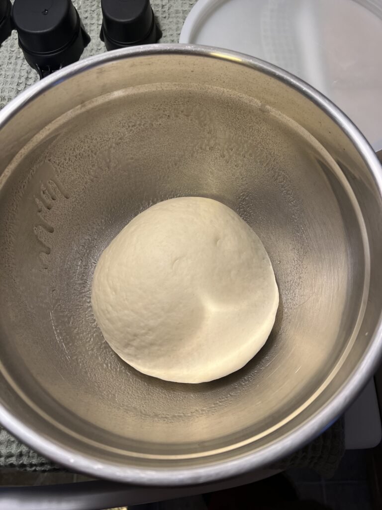 An overhead shot of a Cuisinart nesting bowl with a sourdough bread dough ball. The bowl is greased so the dough won't stick and is ready to be covered and set in a warm place for for the dough's bulk rise.