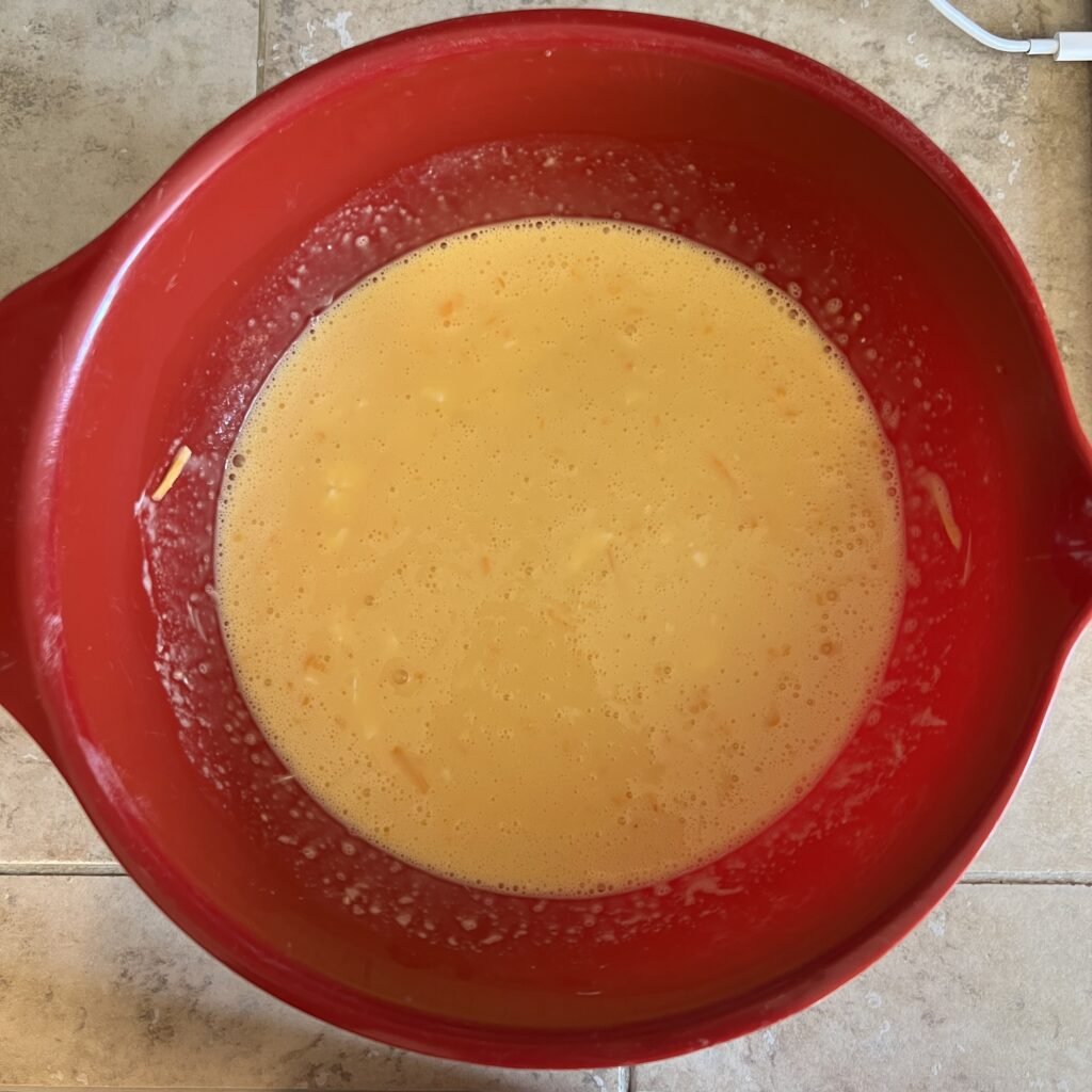 Cheddar egg mixture in a mixing bowl getting ready to be added to a delicious casserole.