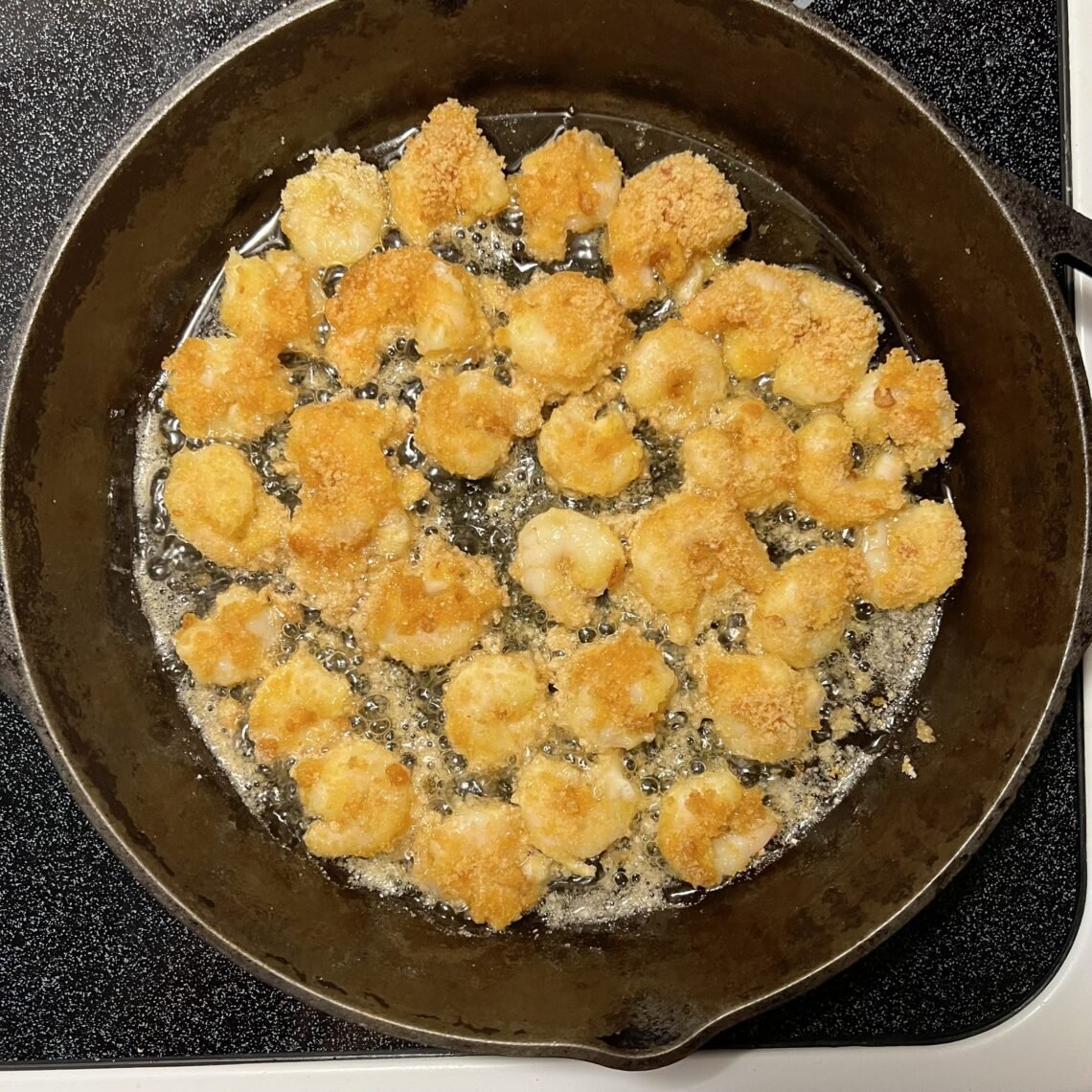 Sizzling low-carb fried shrimp cooking in a skillet on the stove.