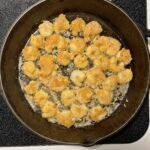 Sizzling low-carb fried shrimp cooking in a skillet on the stove.