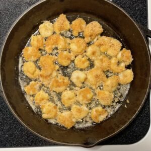 Sizzling low-carb fried shrimp cooking in a skillet on the stove.