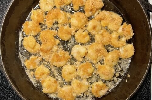 Sizzling low-carb fried shrimp cooking in a skillet on the stove.