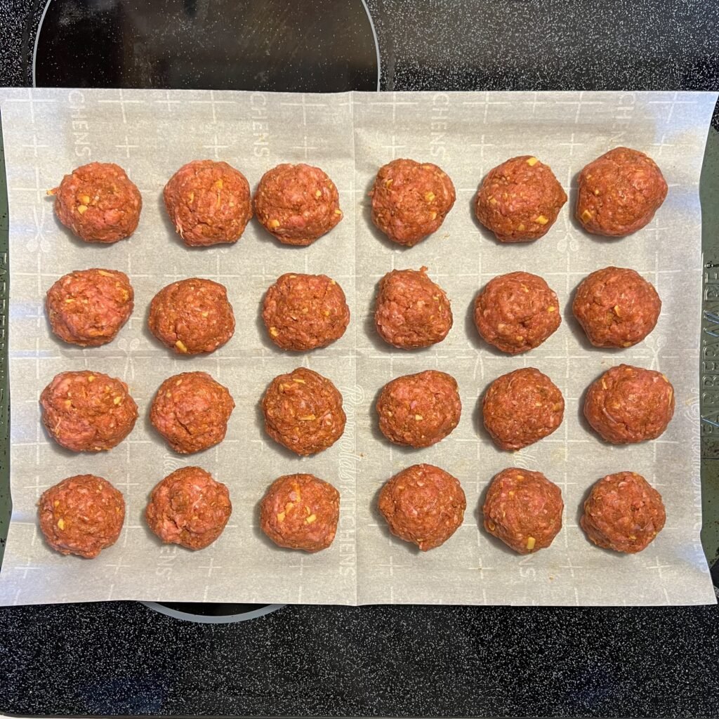 An overhead shot of meatballs on parchment paper ready to be baked to juicy perfection.