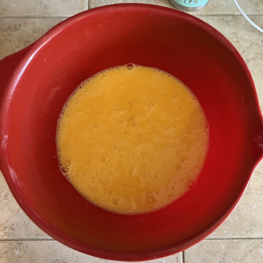 An overhead shot of a bowl of scrambled eggs as part of the base of an easy keto taco casserole.