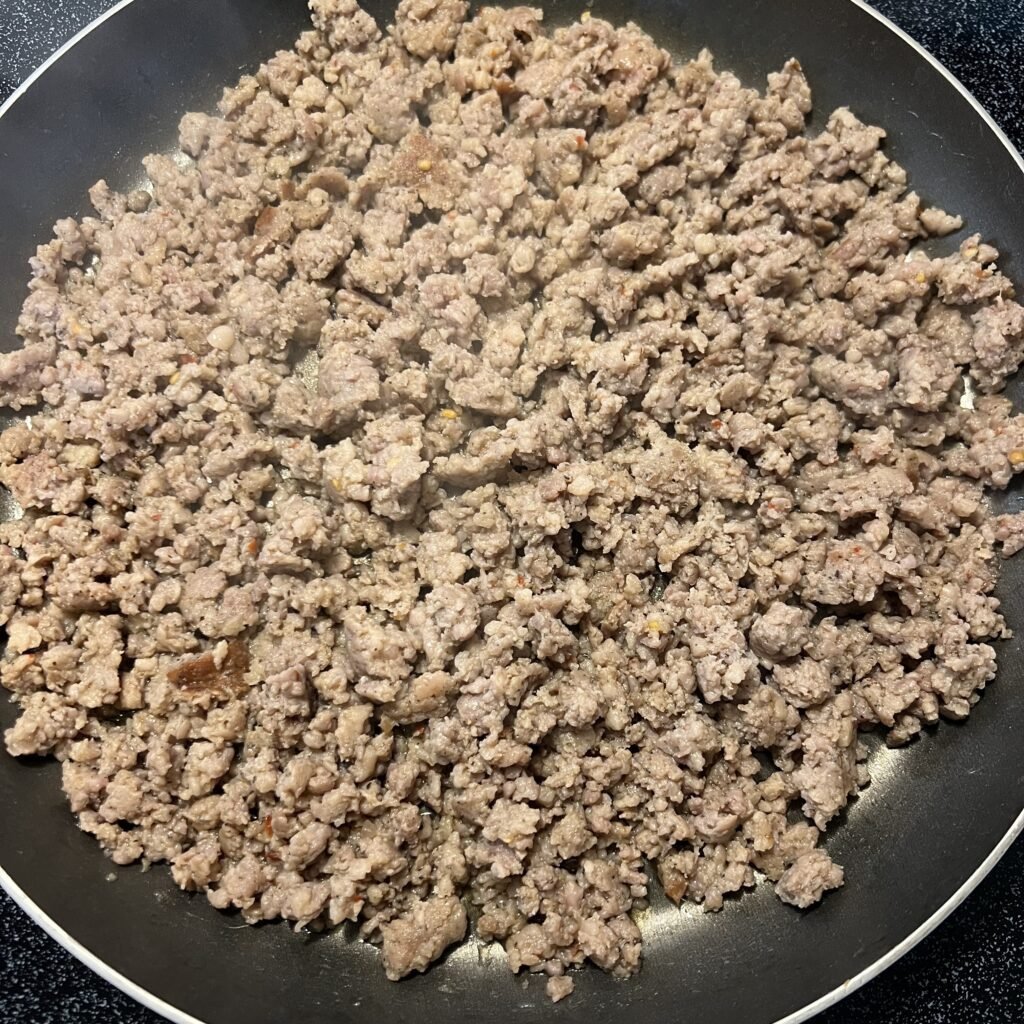 Cooked ground breakfast sausage in a large frying pan on the stovetop.