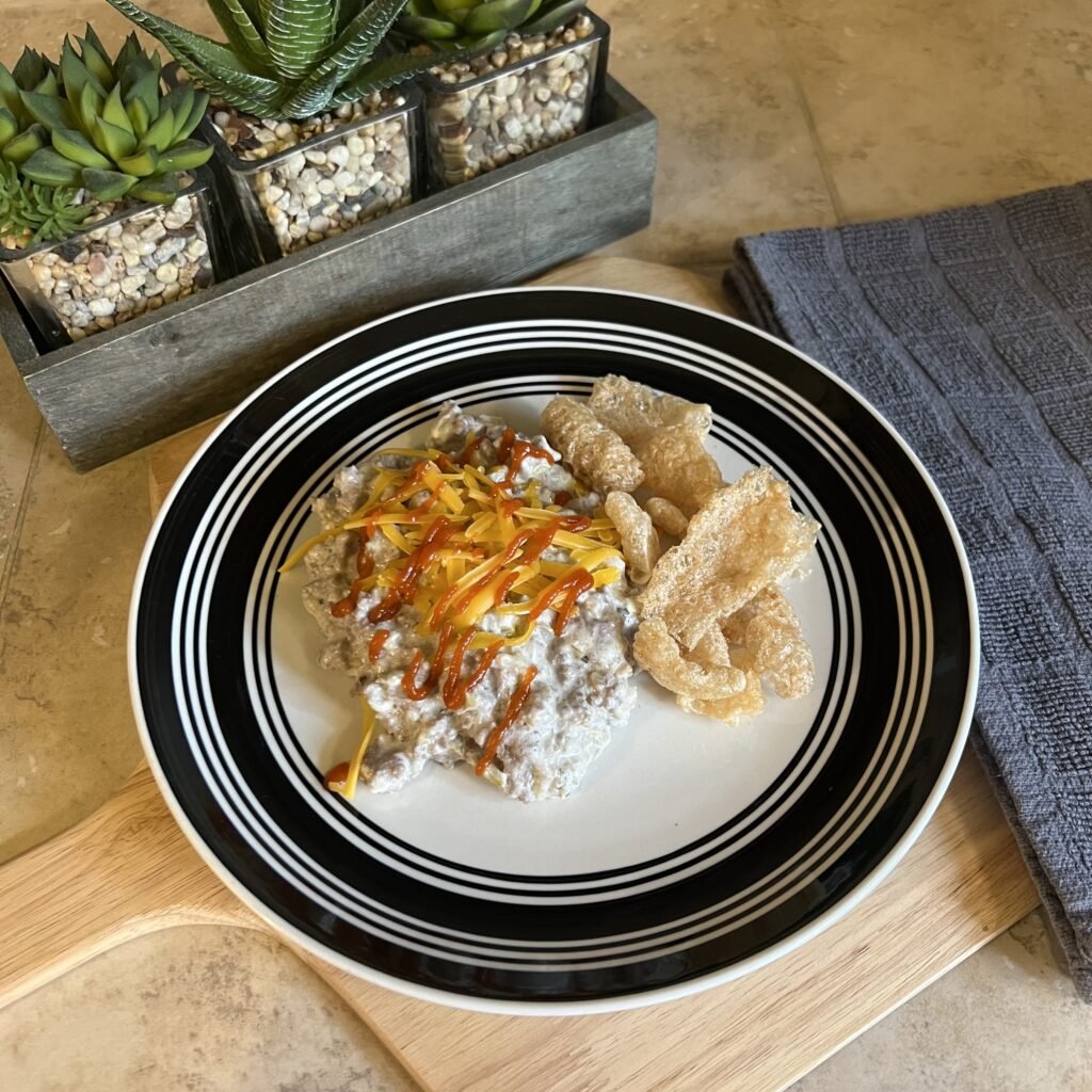 A plate of Creamy Salsa Verde Ground Beef Skillet served with pork rinds and sitting on a beautiful kitchen counter top next to bright green succulants.