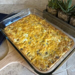 A side shot of a freshly baked keto breakfast casserole on the count with a blue towel and succulent plants in the background.