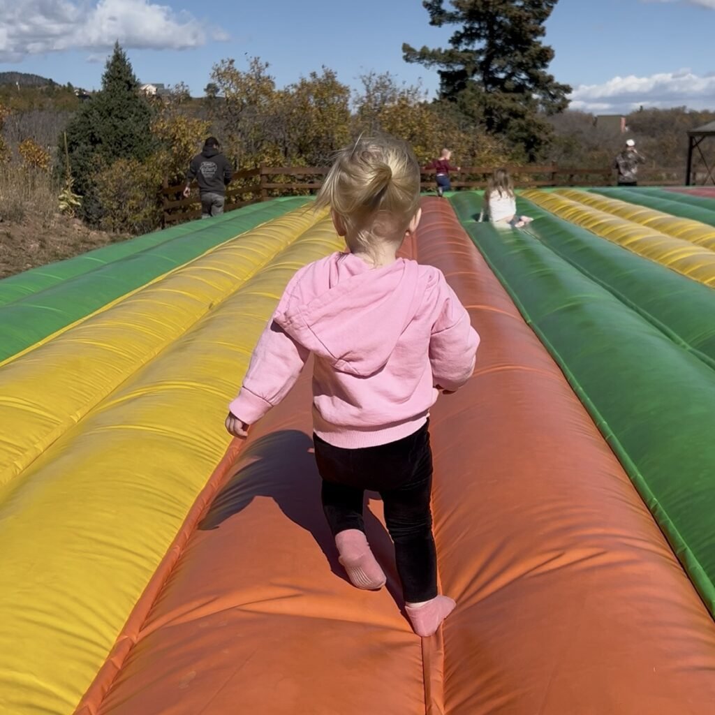 Our toddler playing on the huge jump pad during our pumpkin patch family tradition.