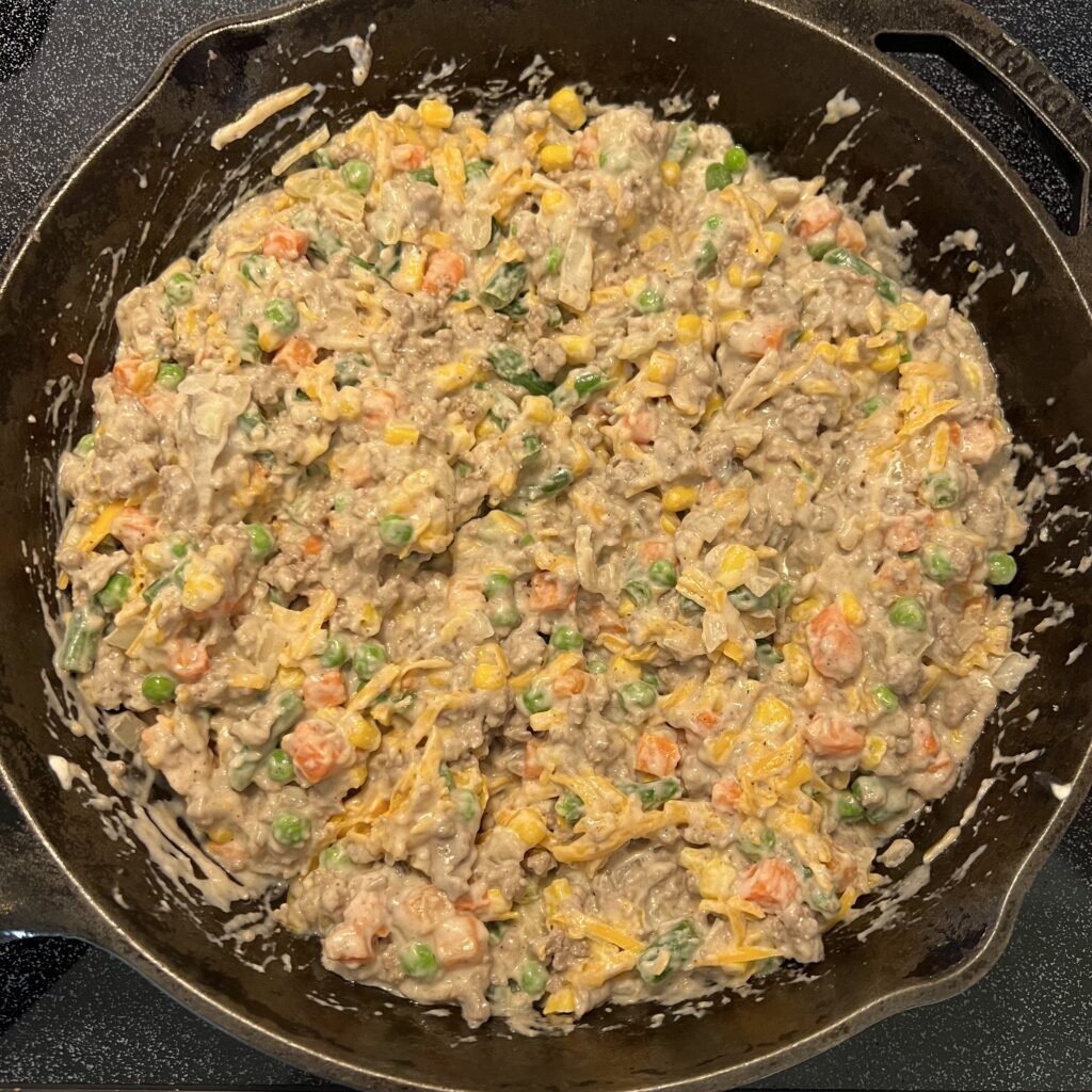 Classic Tater Tot Casserole filling heating up in a cast iron skillet.