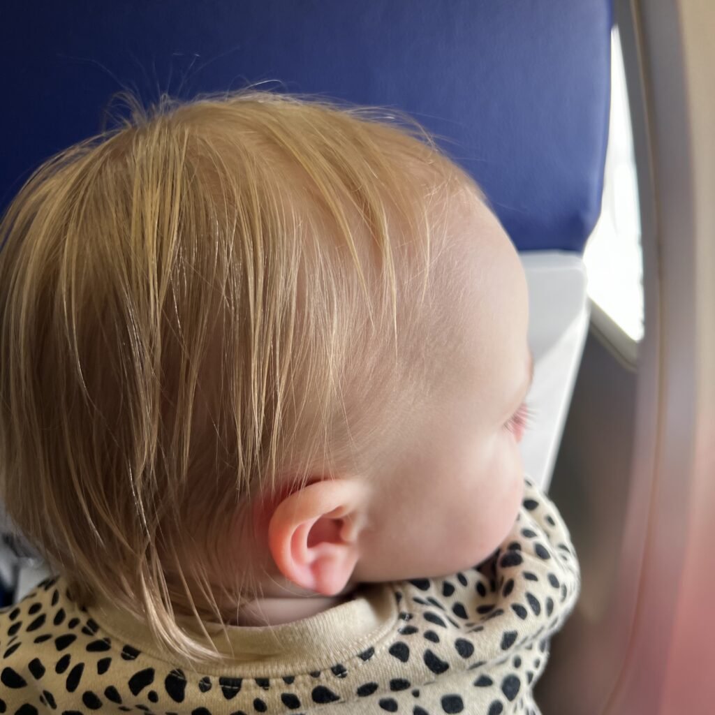 A close-up shot of a toddler on an airplane. 7 packing tips for flying solo with a toddler.