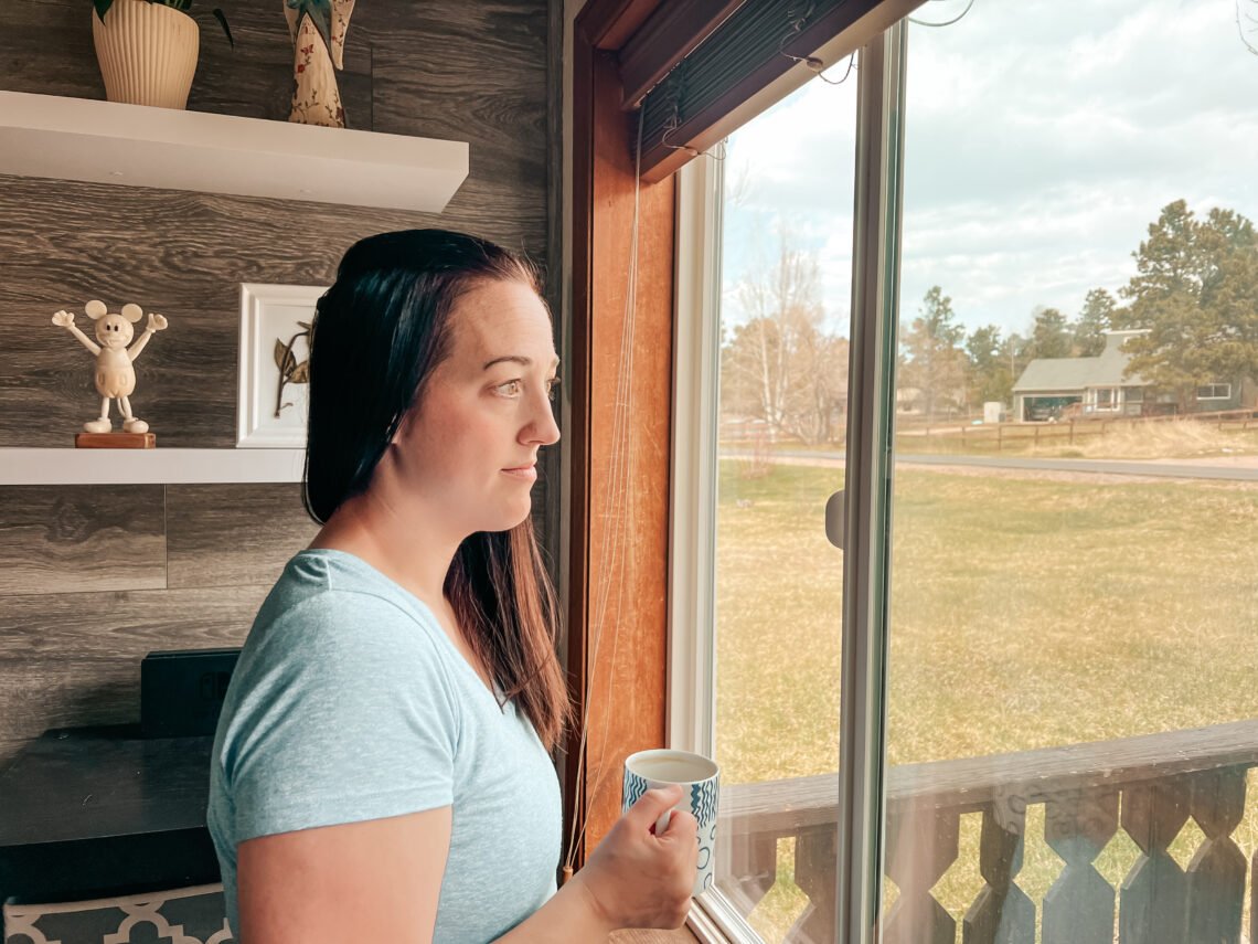 A busy mom standing by the window, finding rest in Jesus.